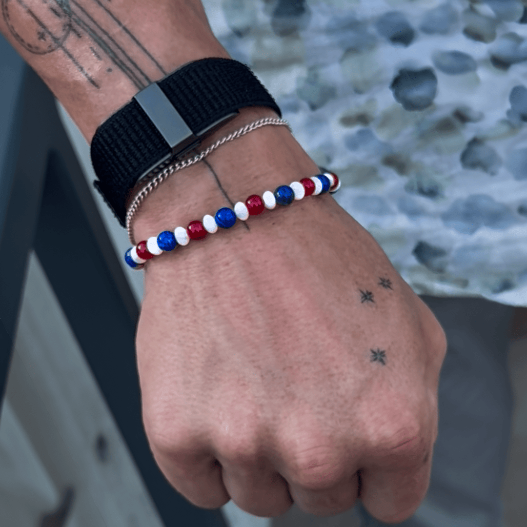 Liberty Lapis Ashton Edition bracelet worn below a black watch on a tattooed wrist outdoors