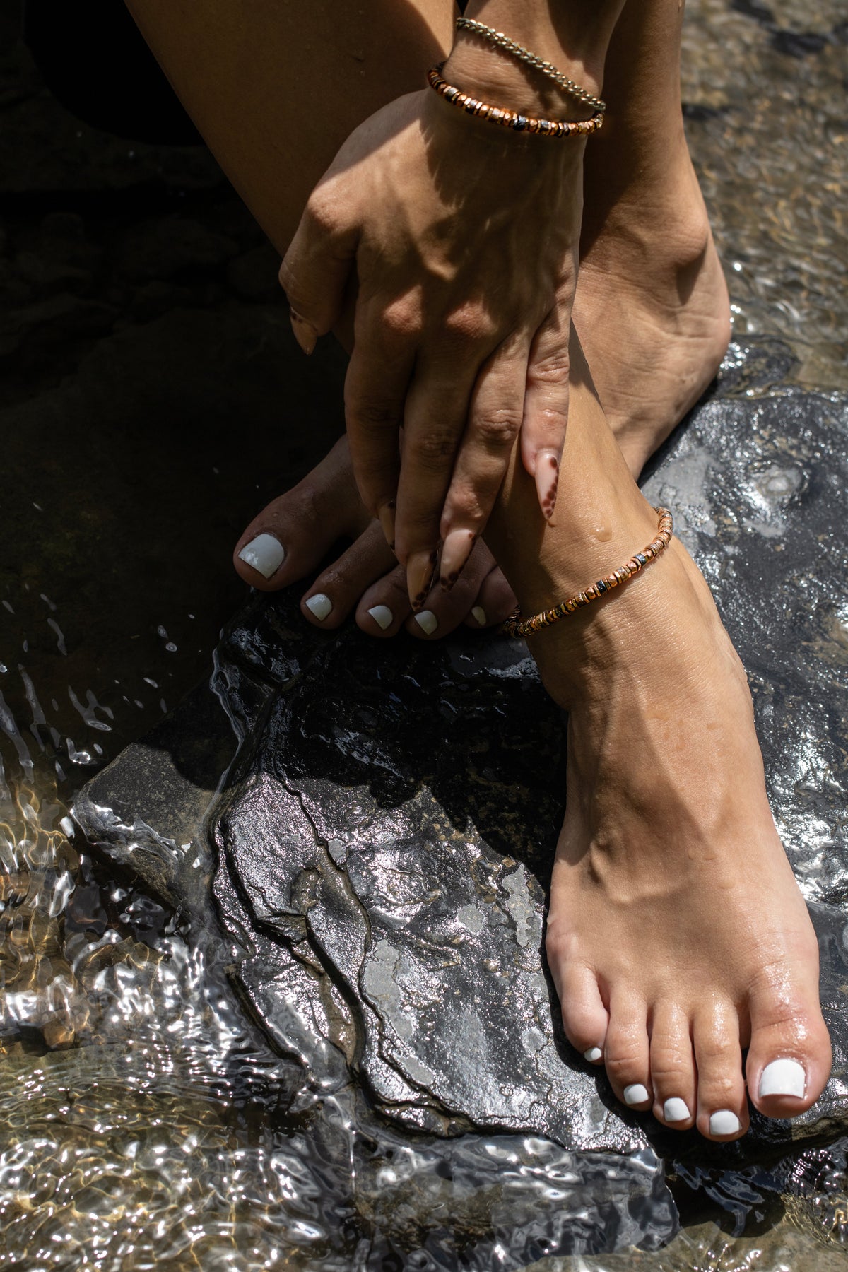 Multicolor crystal anklet worn at the water's edge