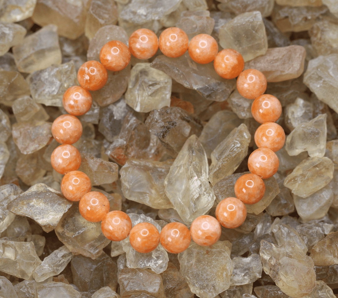 Orange gemstone stretch bracelet displayed on natural quartz crystals