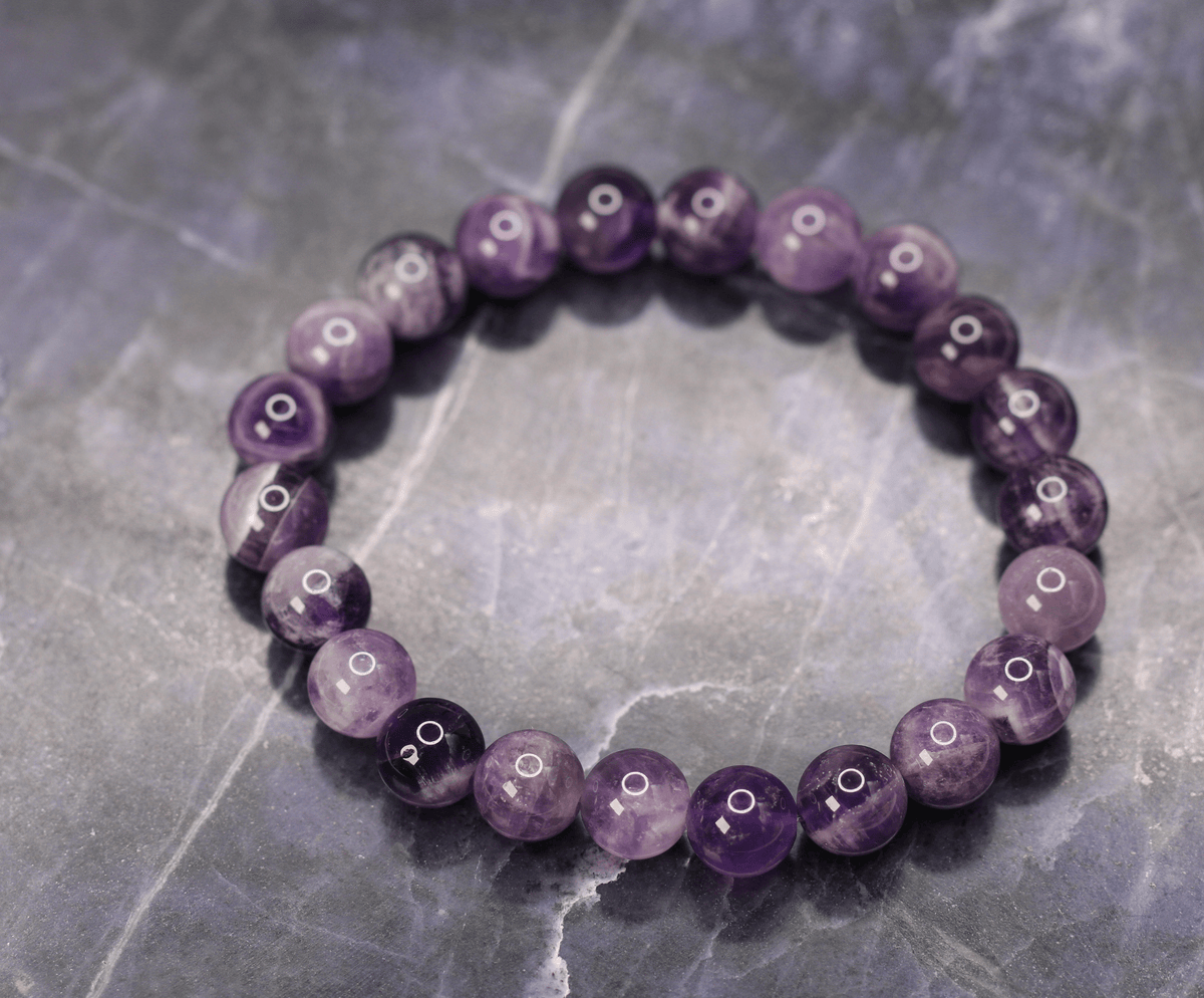 Purple gemstone stretch bracelet displayed on an amethyst-colored stone