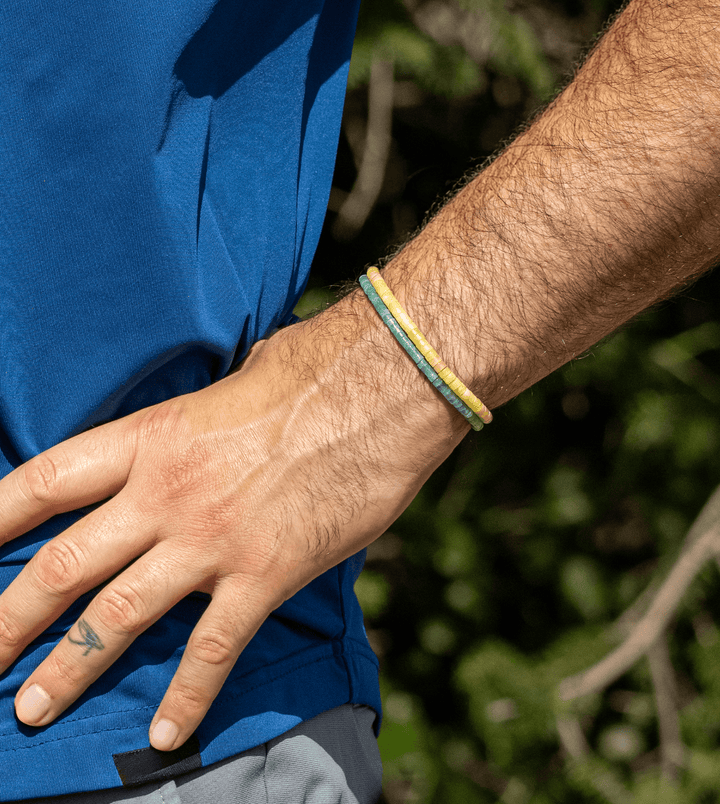 Amazonite Heishi bracelet stacked with yellow and green bracelets on a wrist outdoors