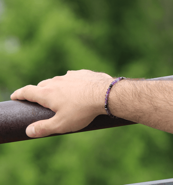 Amethyst Element bracelet on a wrist resting against an outdoor railing