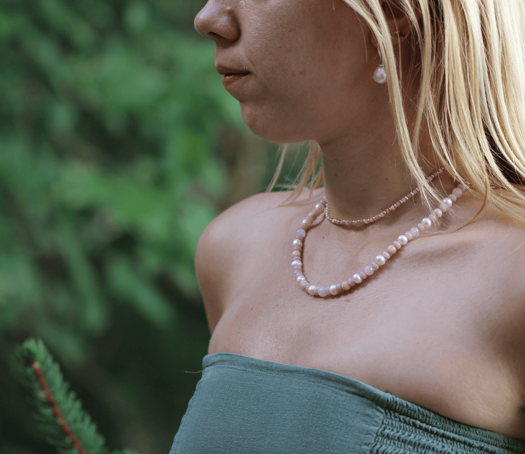 Blossom pearl and pink opal necklace layered with a second pink pearl necklace outdoors