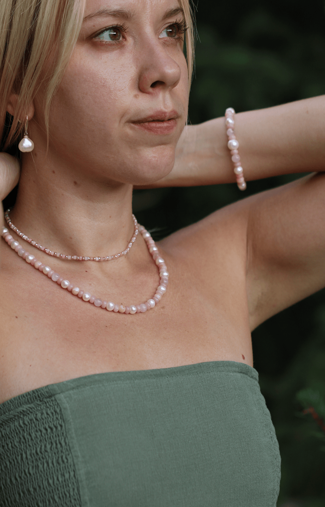 Blossom pearl and pink opal necklace worn with matching pink and pearl bracelets outdoors