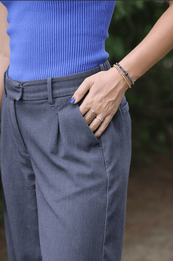 Earthrise bracelet stacked with a slim gold-tone bracelet on a wrist beside a blue top