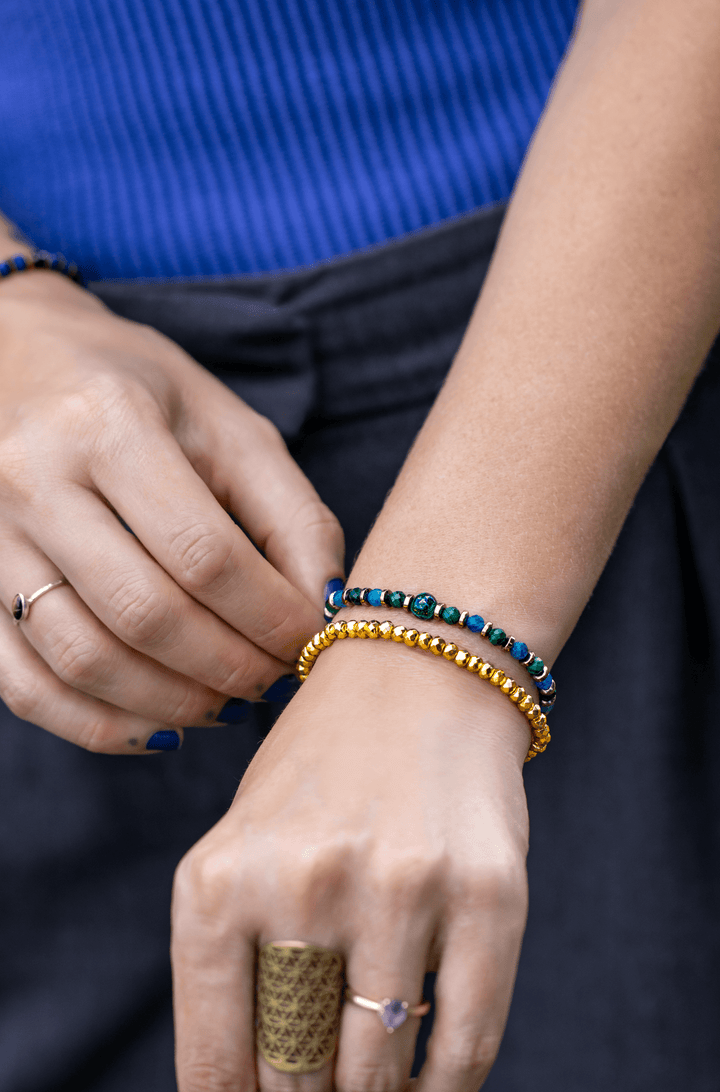 Earthrise bracelet stacked with gold-tone beads on a wrist beside a blue top