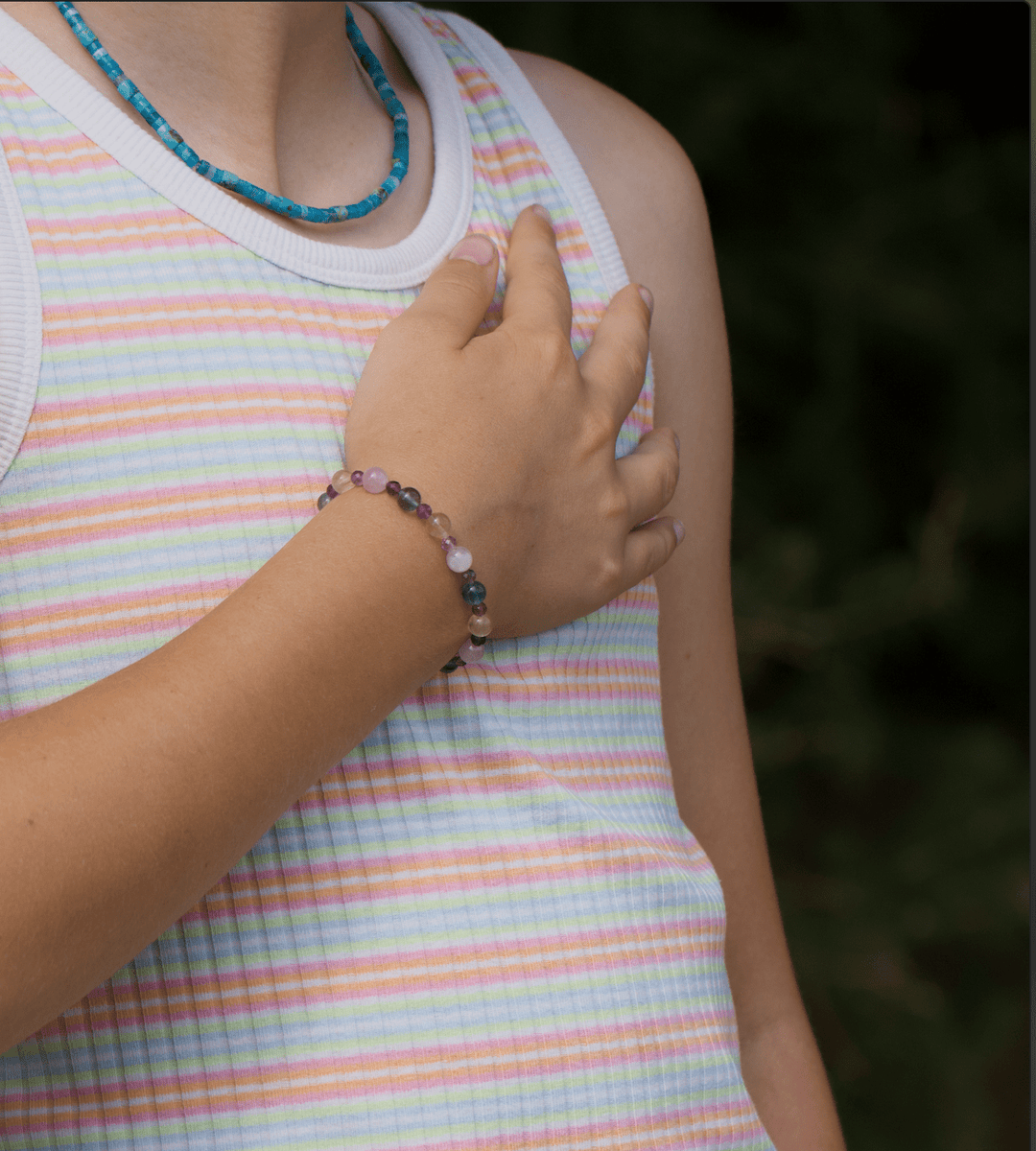 Fairy bracelet worn on a wrist with a colorful beaded necklace and pastel striped top