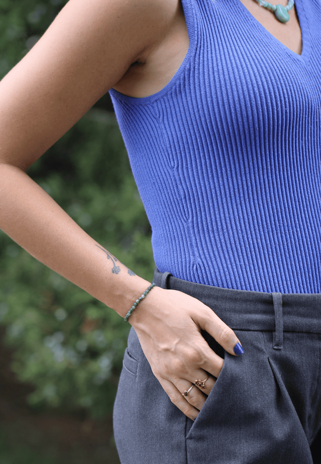 Green kyanite bracelet worn alone on a wrist with hand in pocket beside a blue top