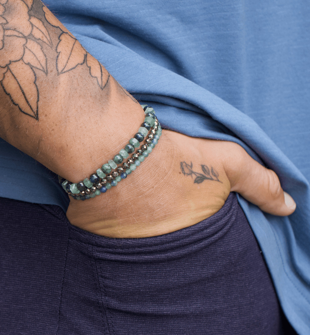Green kyanite, Ivy, and faceted pyrite bracelets stacked on a tattooed wrist