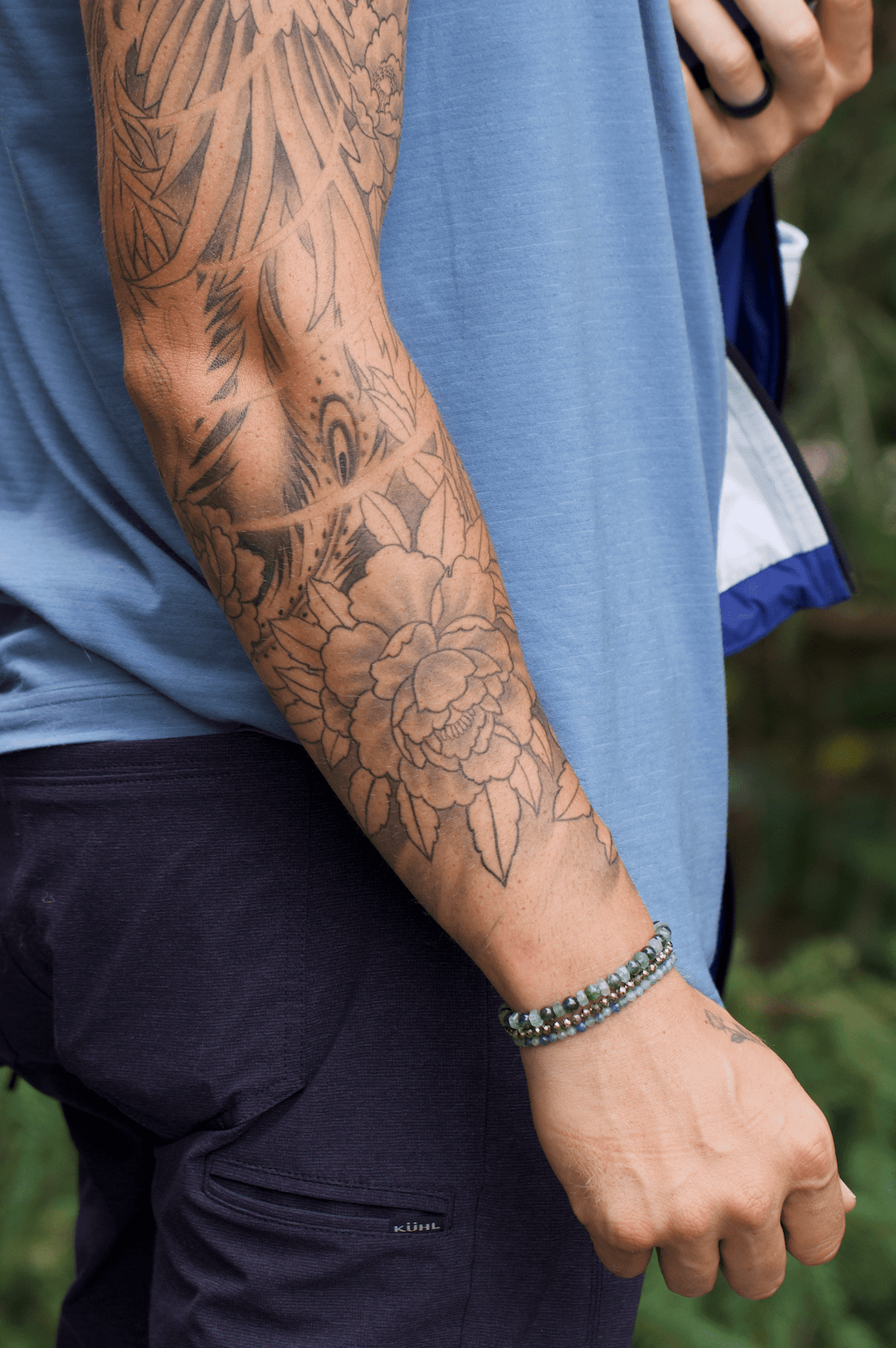 Green kyanite, Ivy, and faceted pyrite bracelet stack on a tattooed forearm outdoors