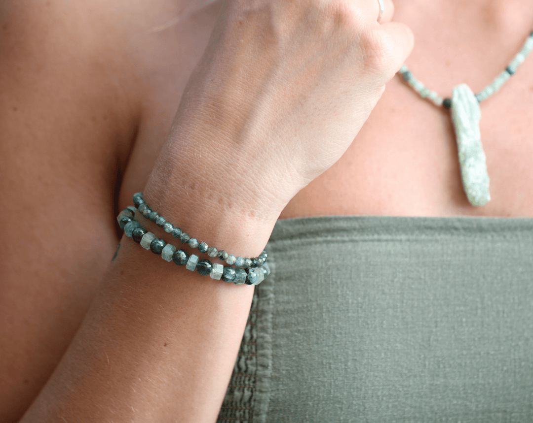Green kyanite and Ivy green chalcedony bracelets stacked on a wrist beside a green top