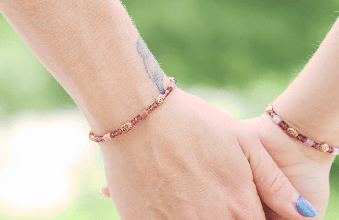 Willow pink-purple garnet and petrified rhodonite bracelets on two people holding hands outdoors