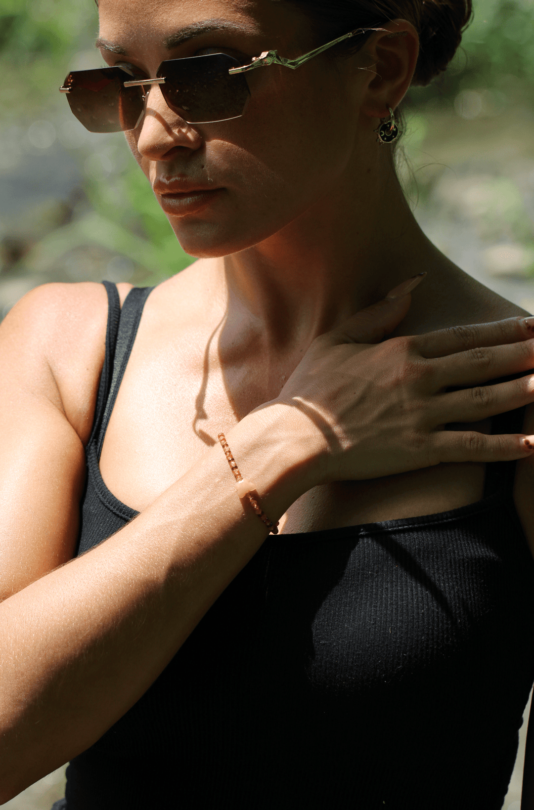 Monarch orange gemstone bracelet worn by a model in a black top outdoors