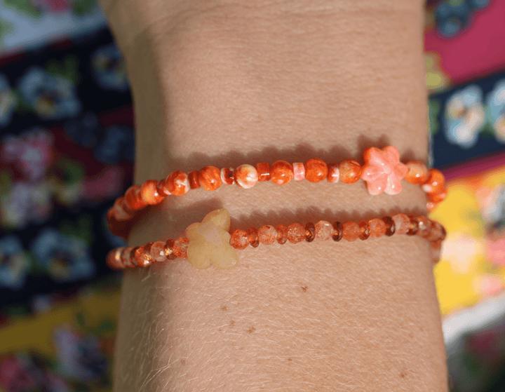 Monarch butterfly and Zuni daisy gemstone bracelets stacked on a wrist