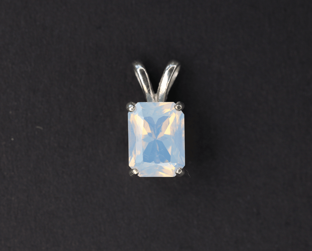 Rectangular Oregon opal pendant in a silver prong setting against black