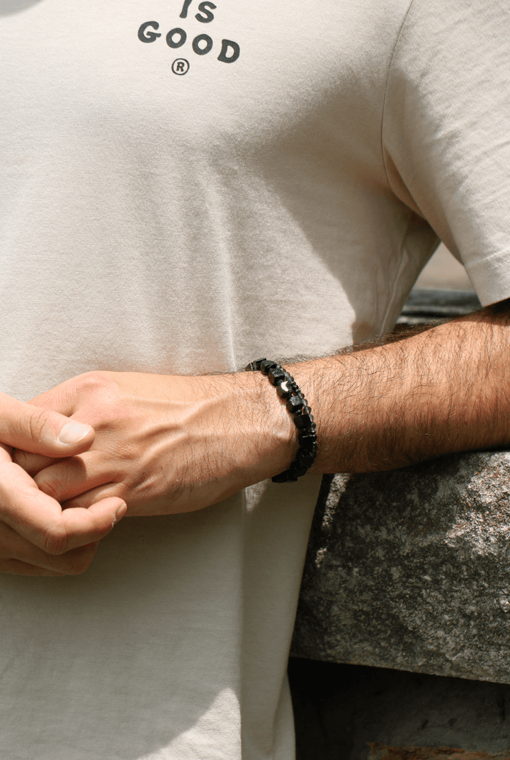 Paint It Black black tourmaline bracelet worn by a model leaning against stone