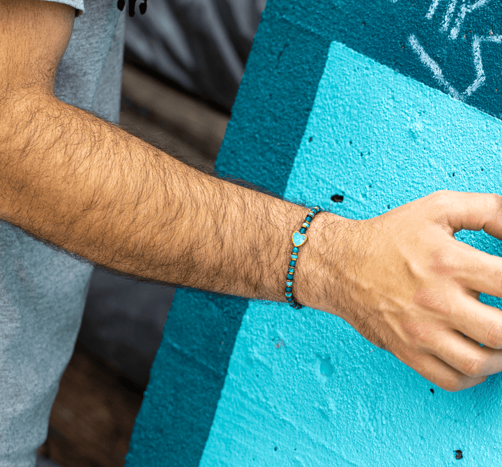 Patina Heart bracelet on a tattooed wrist resting against a turquoise block