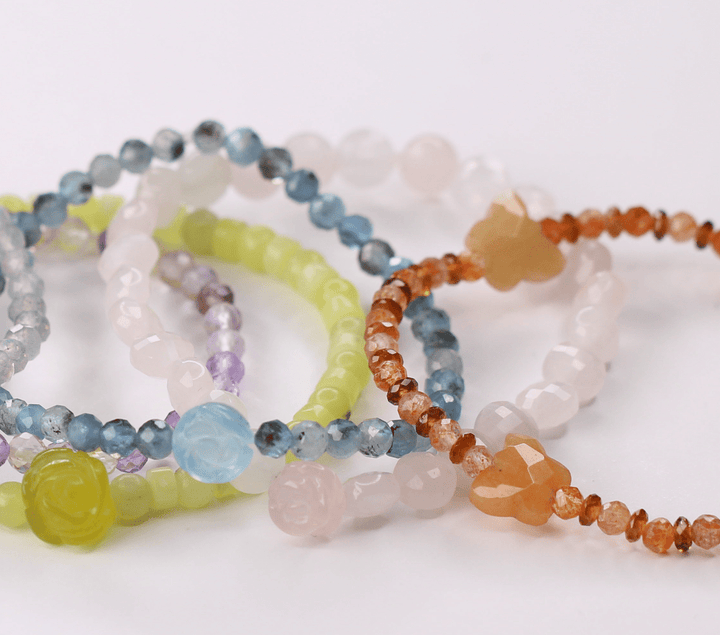 Pastel crystal bracelet collection including Rose and Monarch designs in a styled flat lay
