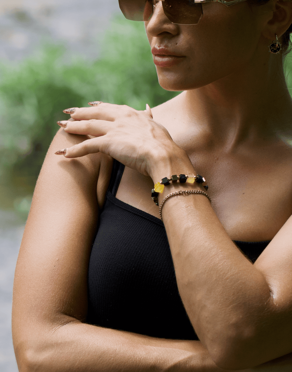 Model wearing the Shep black tourmaline and yellow fluorite bracelet with arms crossed outdoors