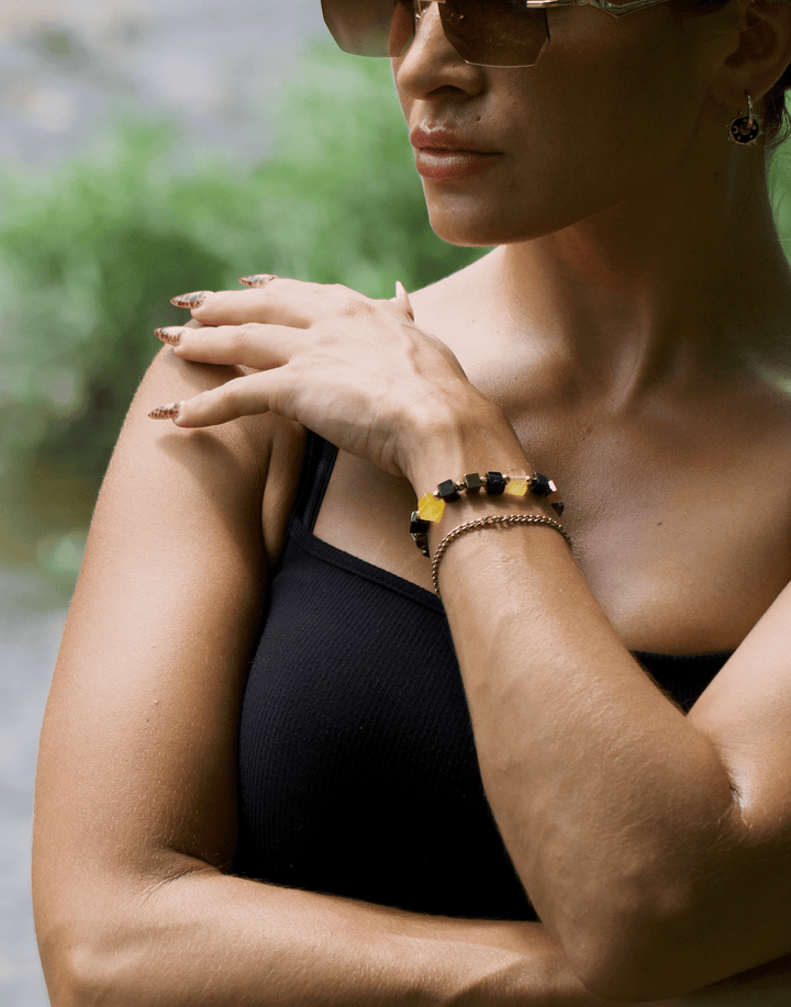 Model wearing the Shep black tourmaline and yellow fluorite bracelet with arms crossed outdoors