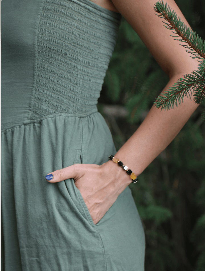 Shep black tourmaline and yellow fluorite bracelet beside a hand in a dress pocket