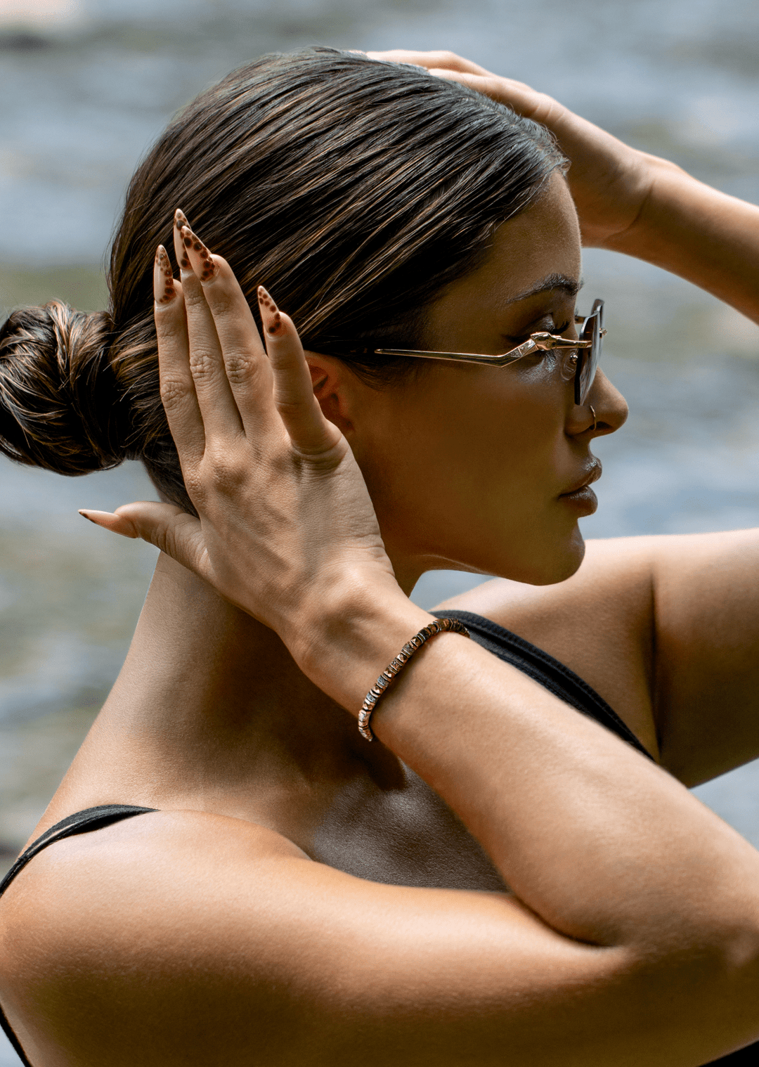 Side view of a model wearing the Tawny bronze biotite mica and titanium hematite bracelet with arms raised