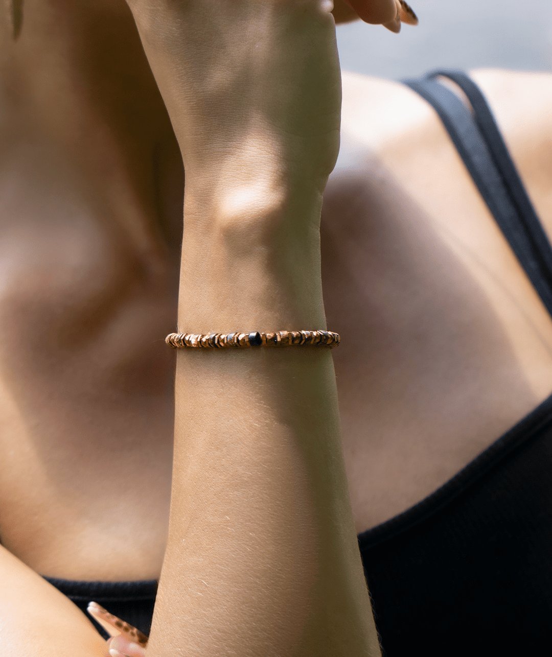 Tawny bronze biotite mica and titanium hematite bracelet on a raised wrist