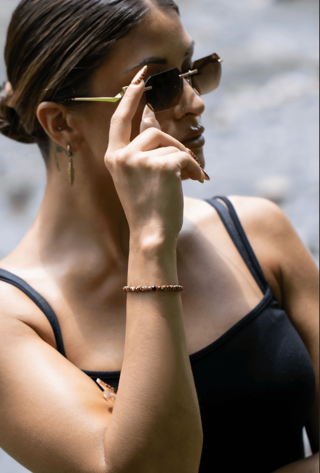 Model wearing the Tawny bronze biotite mica and titanium hematite bracelet while adjusting sunglasses