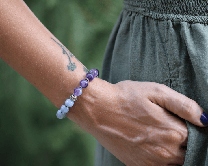 Teach kunzite and amethyst bracelet on a model’s wrist against a sage green dress