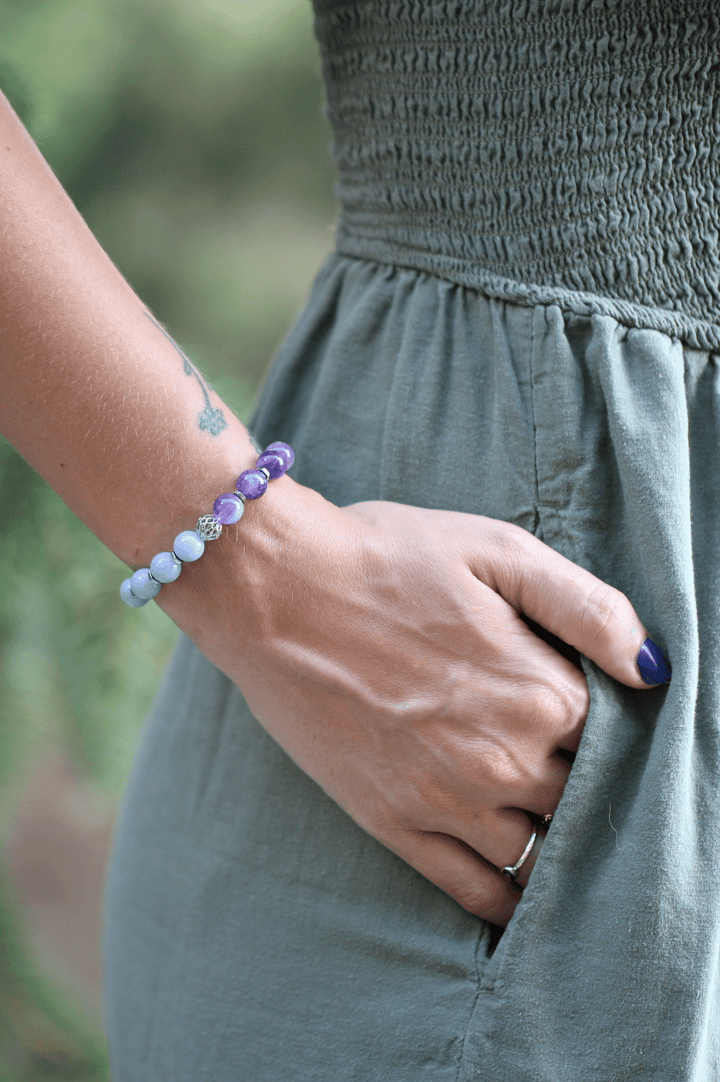Teach kunzite and amethyst bracelet beside a hand in a dress pocket