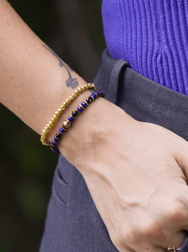 Titanium Hematite Rondelle bracelet stacked with purple beads on a wrist at the waist