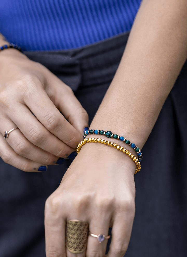 Titanium Hematite Rondelle bracelet in a colorful stack on a hand near gray trousers