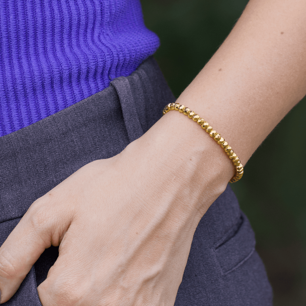 Titanium Hematite Rondelle bracelet shown close at the waist beside a blue top and gray trousers