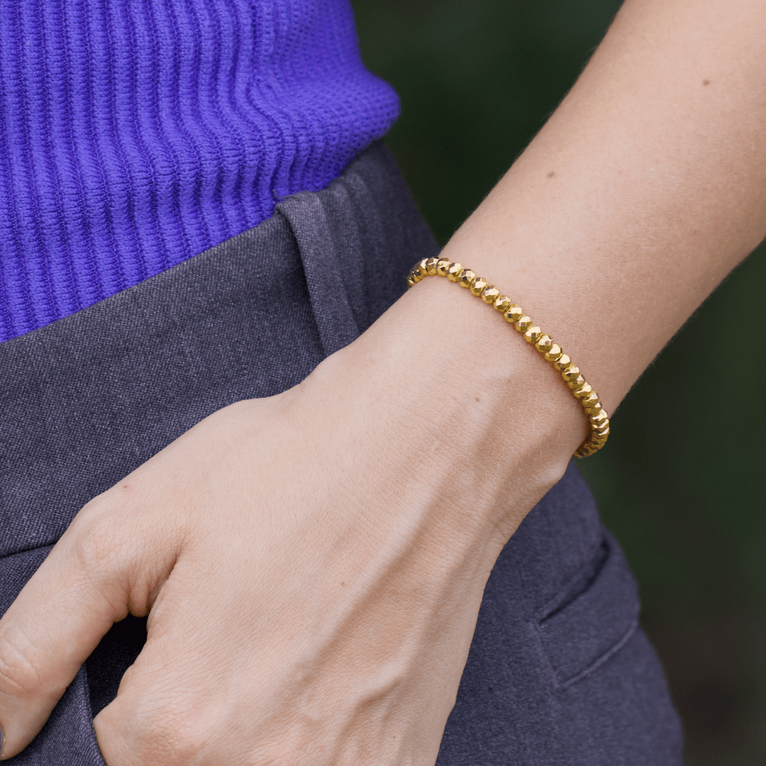 Titanium Hematite Rondelle bracelet shown close at the waist beside a blue top and gray trousers
