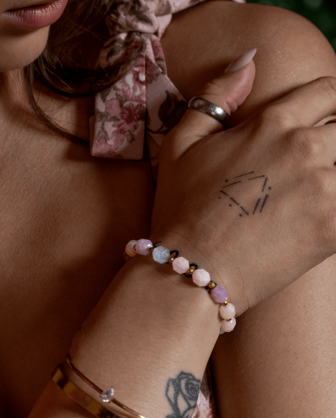 True Spring aquamarine and rose quartz bracelet on crossed hands against a floral dress