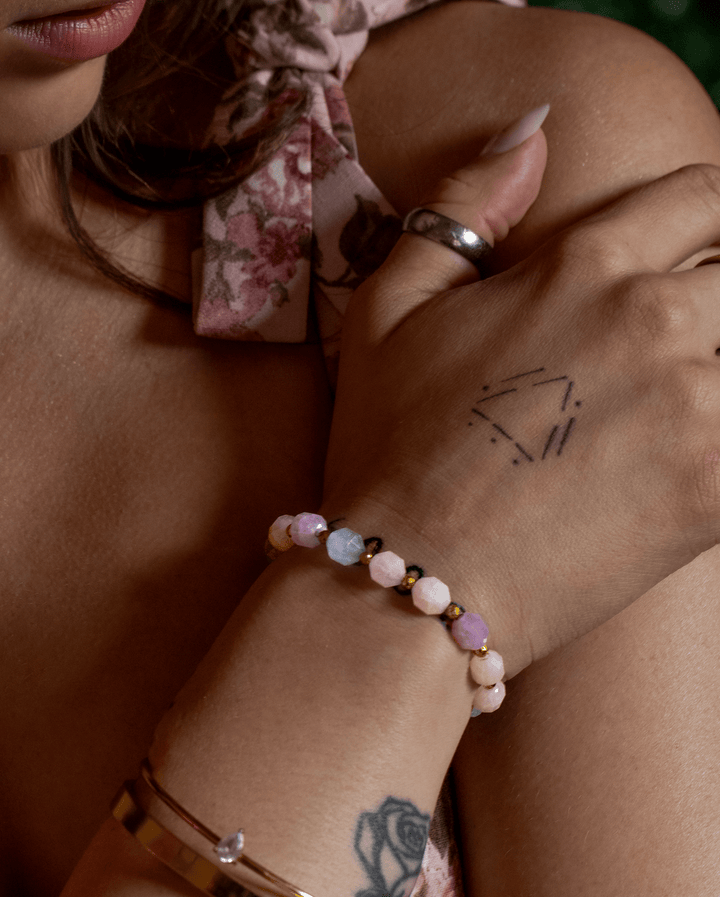 True Spring aquamarine and rose quartz bracelet on crossed hands against a floral dress