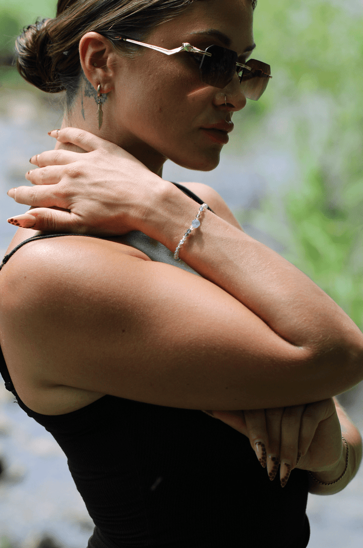 Viola purple amethyst and ametrine bracelet on a raised wrist in an outdoor portrait