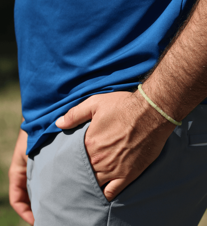 Yellow Jade Heishi bracelet on a wrist with a hand in a pocket beside a blue shirt outdoors