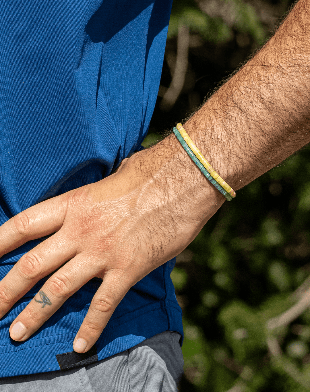 Yellow Jade Heishi bracelet stacked with an aqua bracelet on a wrist outdoors