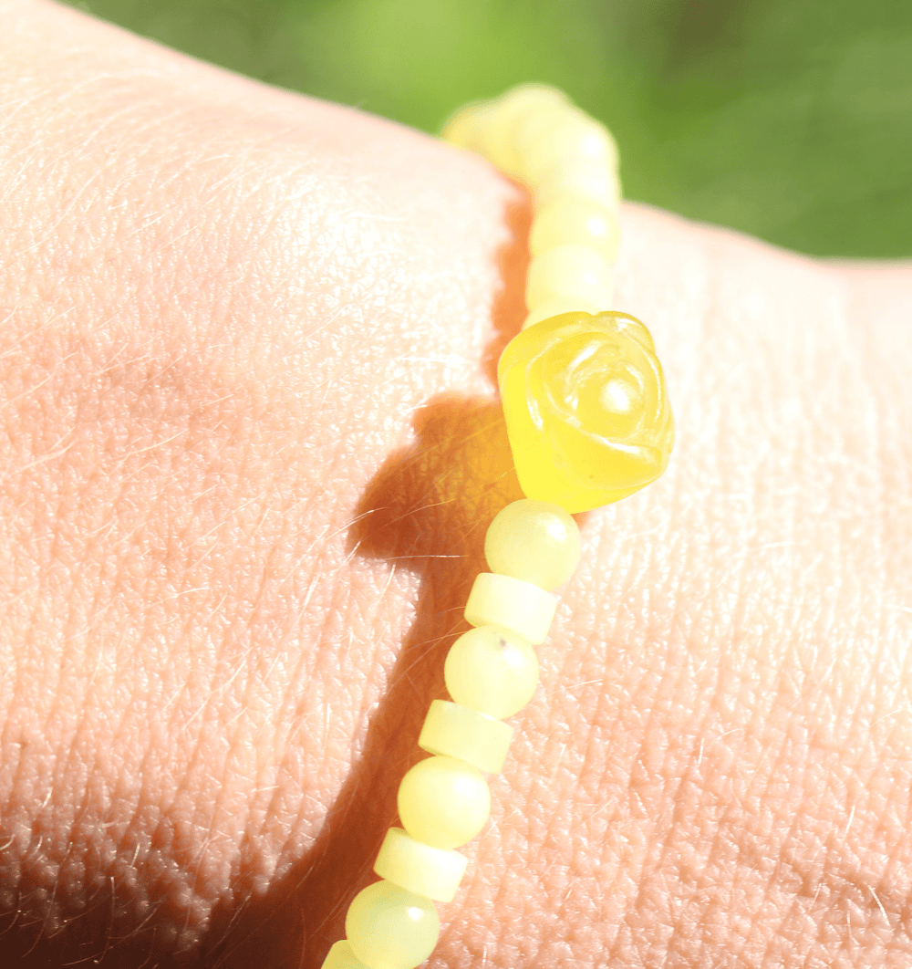Lemon Flower yellow jade bracelet with carved flower bead in sunlight on a wrist
