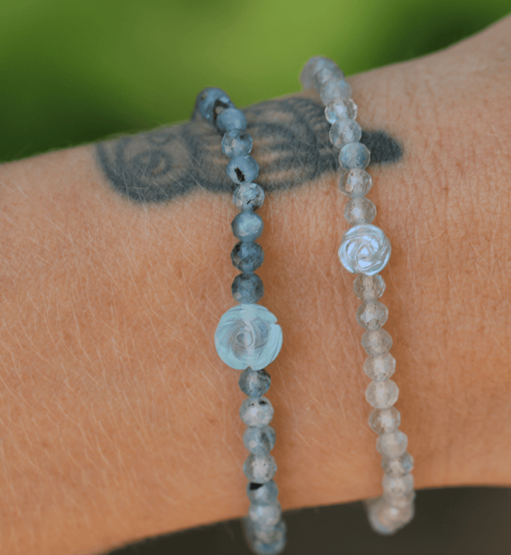 Silver Sage labradorite flower bracelet stacked with blue gemstones on a tattooed wrist