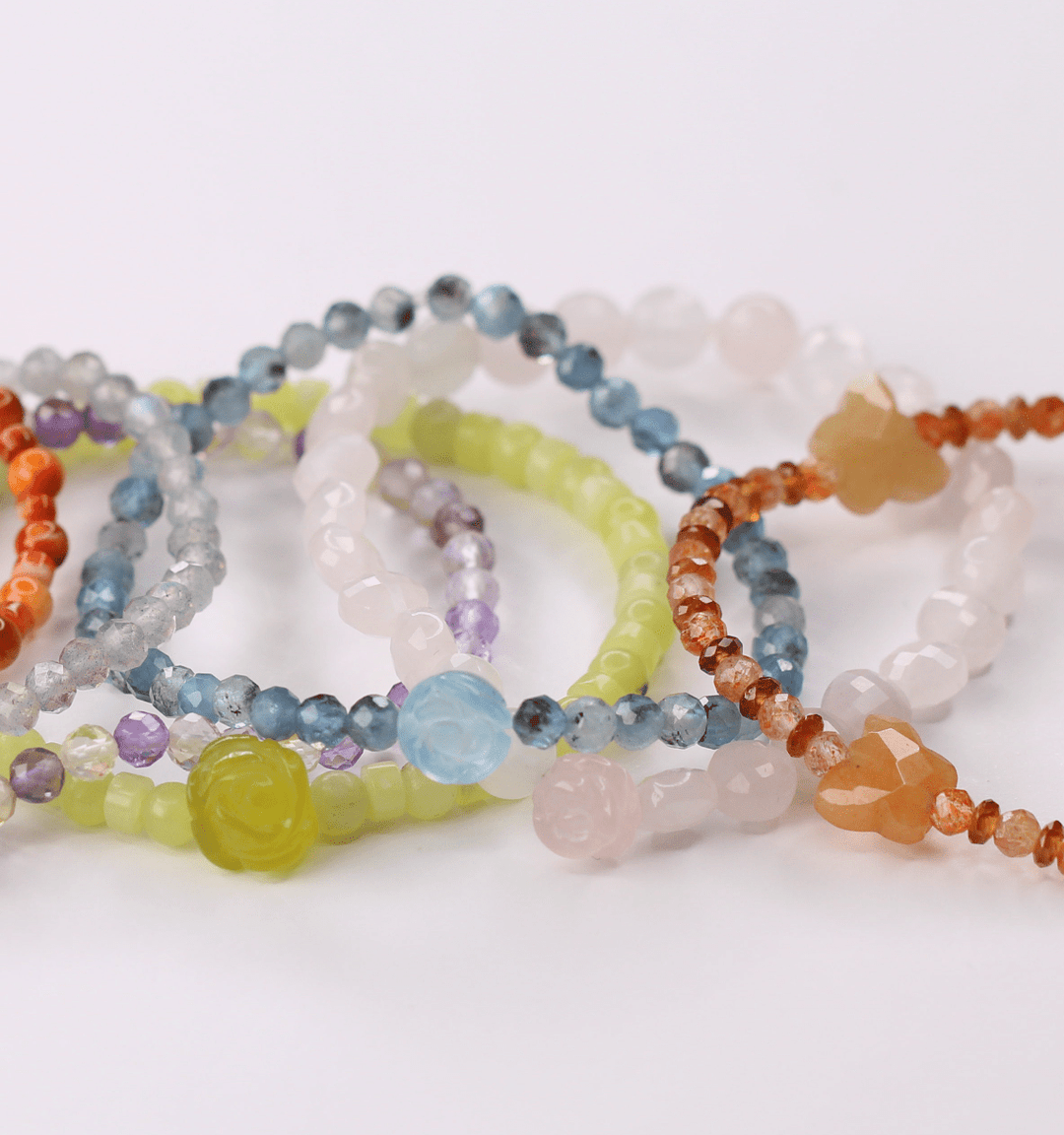 True Compassion aquamarine flower bracelet among colorful crystal bracelets on white